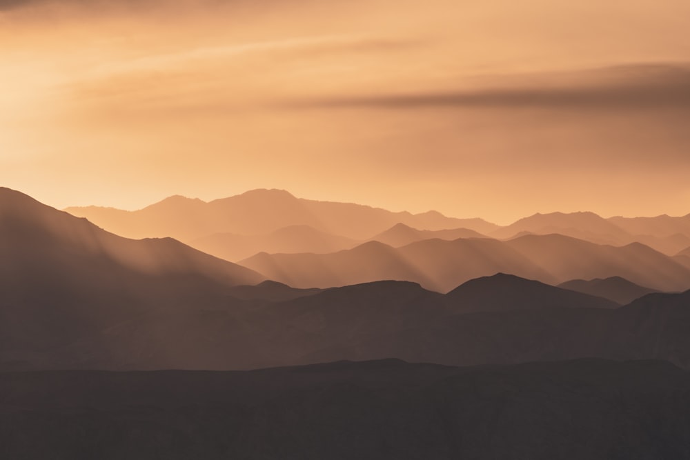 the sun is shining through the clouds over the mountains