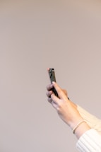 Elegant close-up of a woman’s hand gently holding a smartphone with a soft beige background.