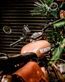 Set of handcrafted leather alforjes attached to a classic motorcycle under warm sunlight.