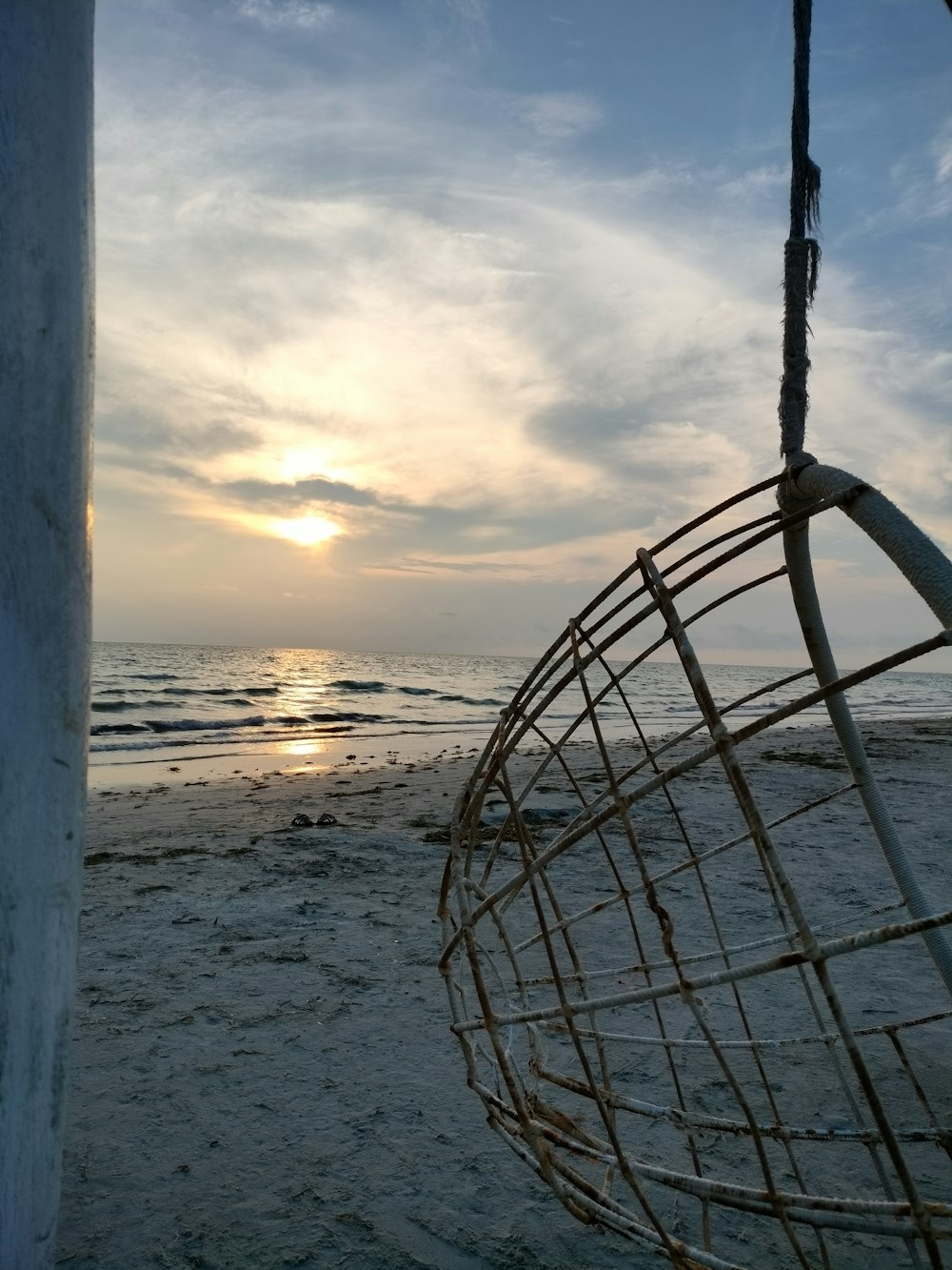 the sun is setting on the beach with a swing