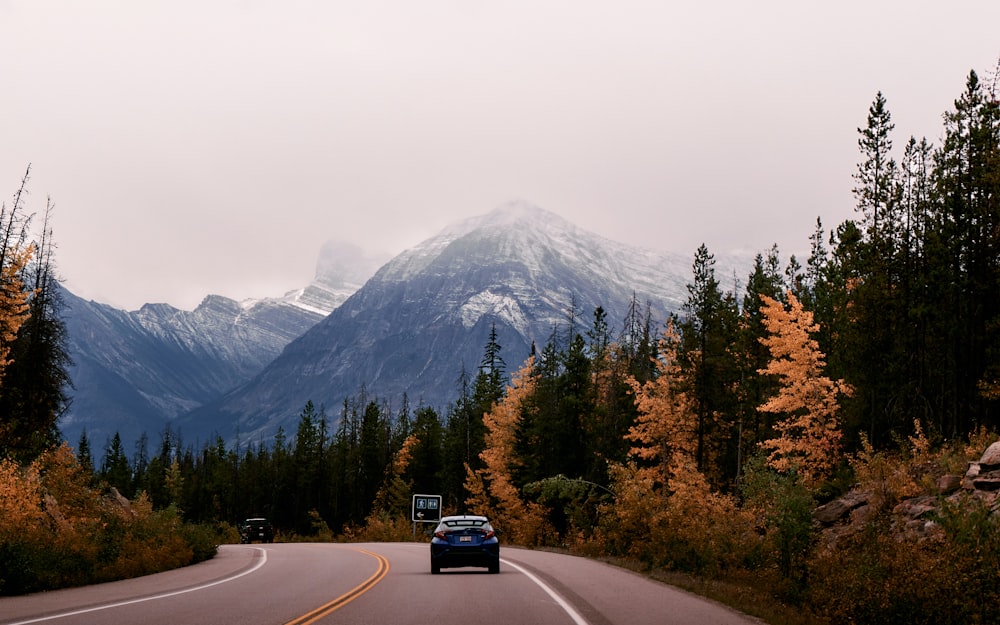 a car driving down a road with mountains in the background