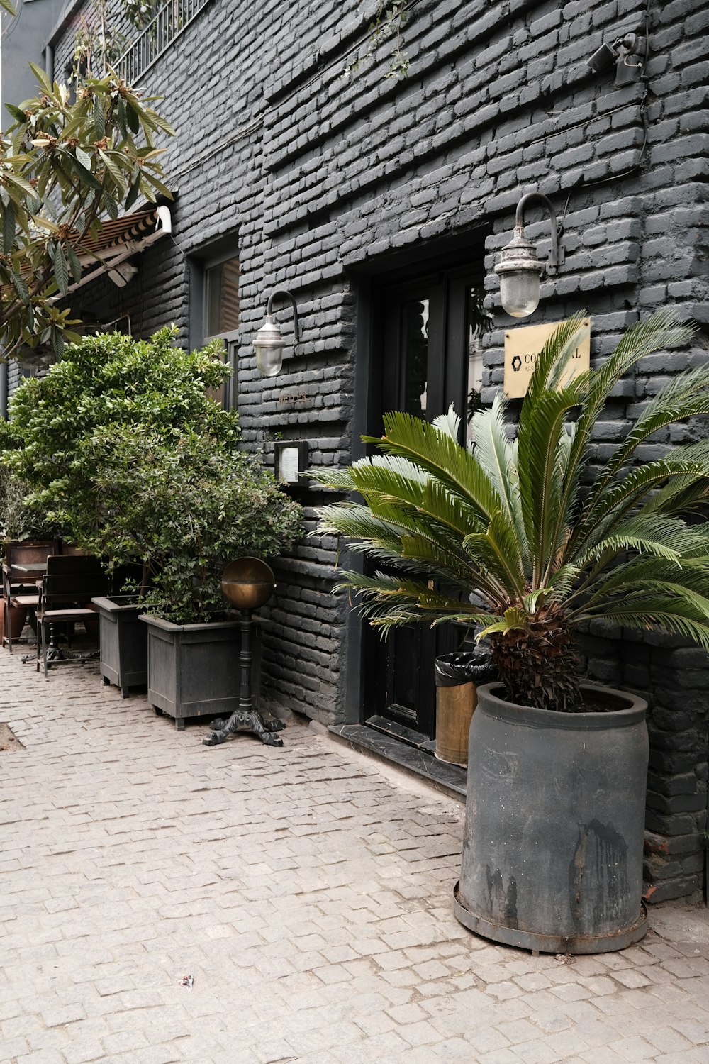a brick building with potted plants on the sidewalk