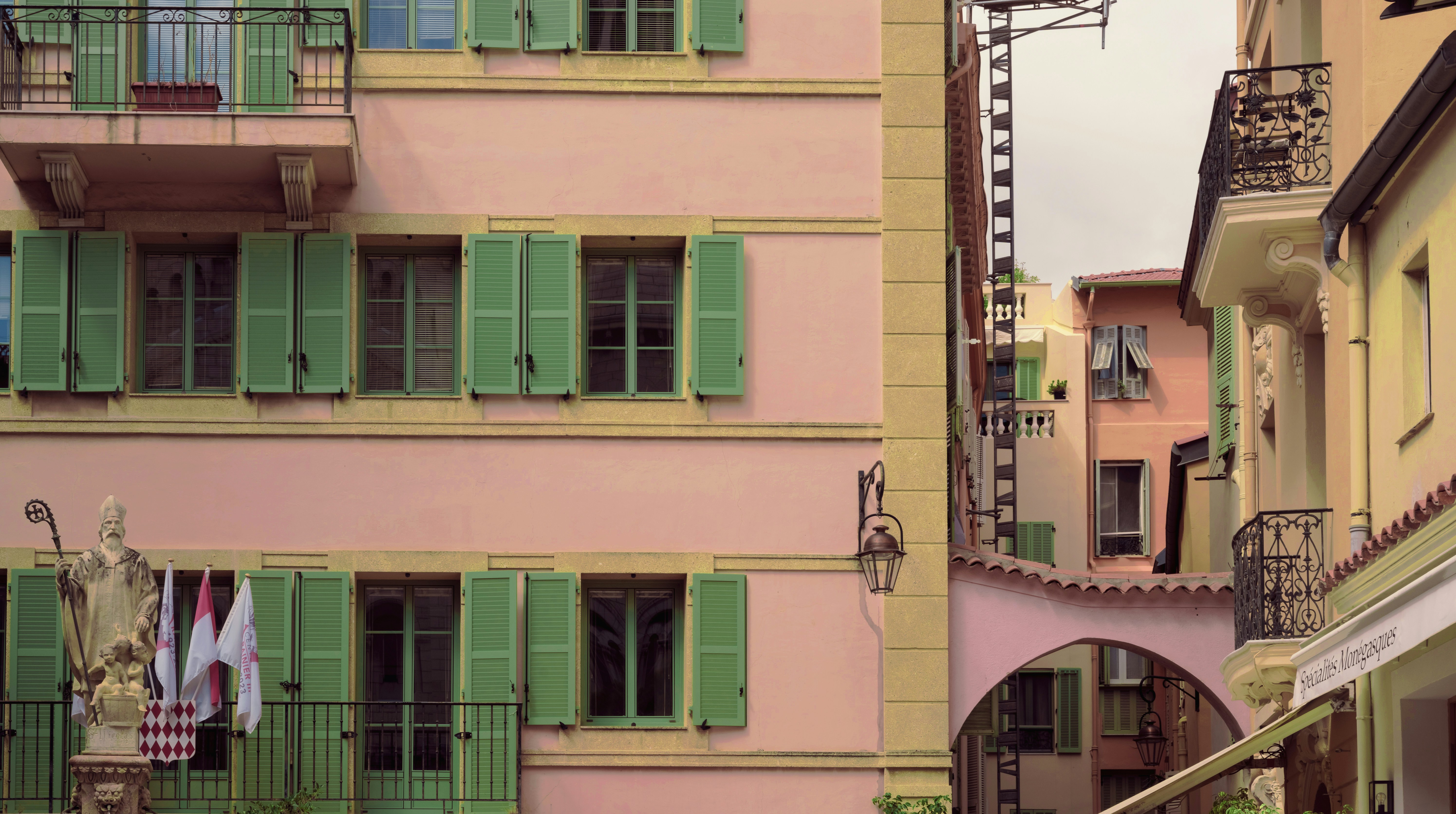 a pink building with green shutters and a clock