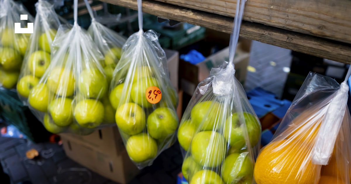 Bags of green apples and oranges hanging from a rack photo – Free ...