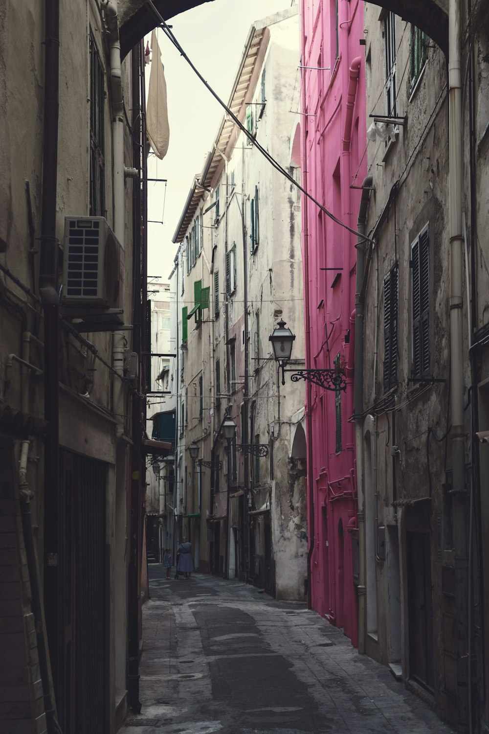 a narrow city street with a pink door