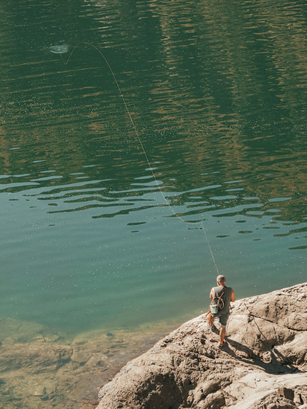 a man standing on top of a rock next to a body of water