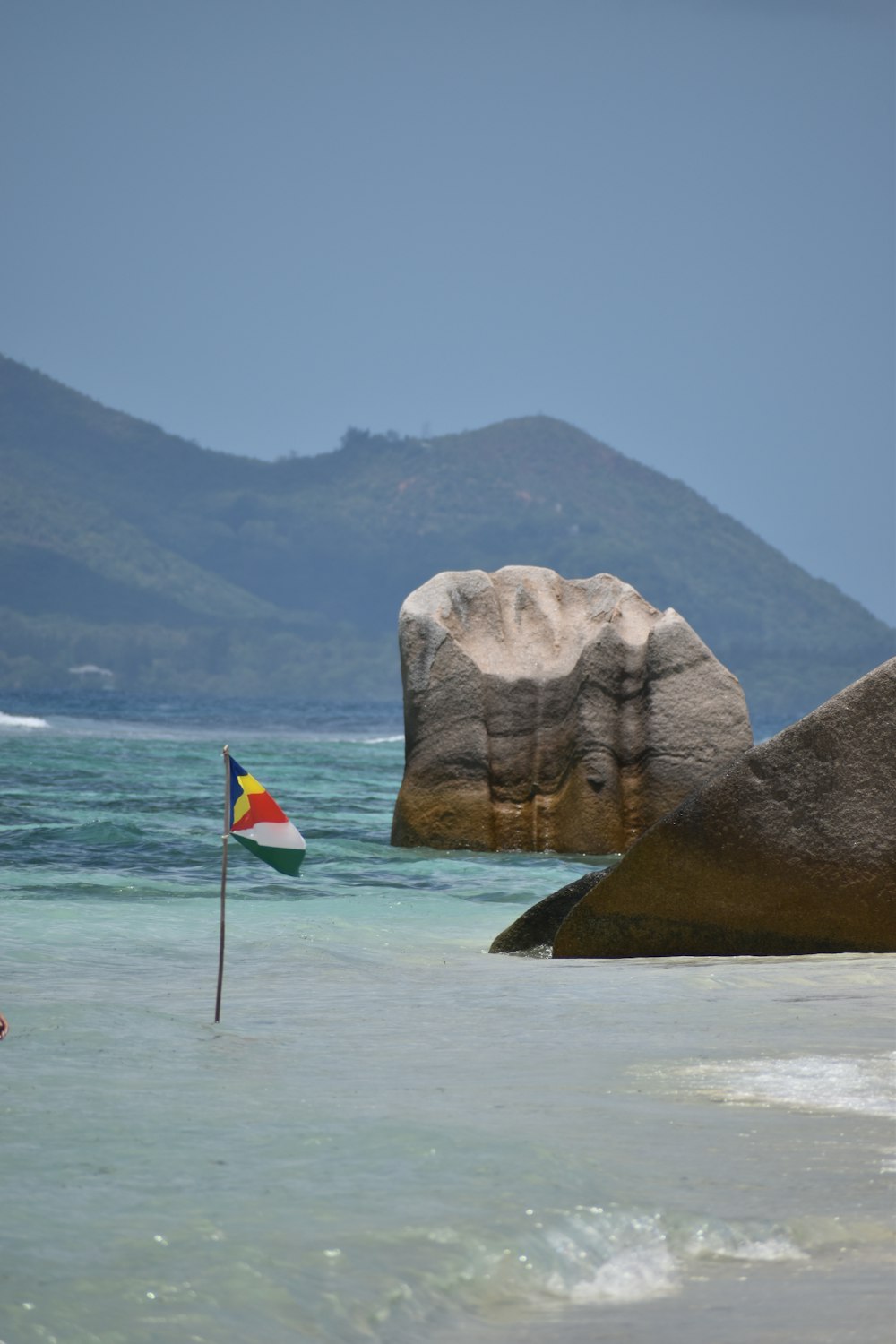 a flag is in the water next to a large rock