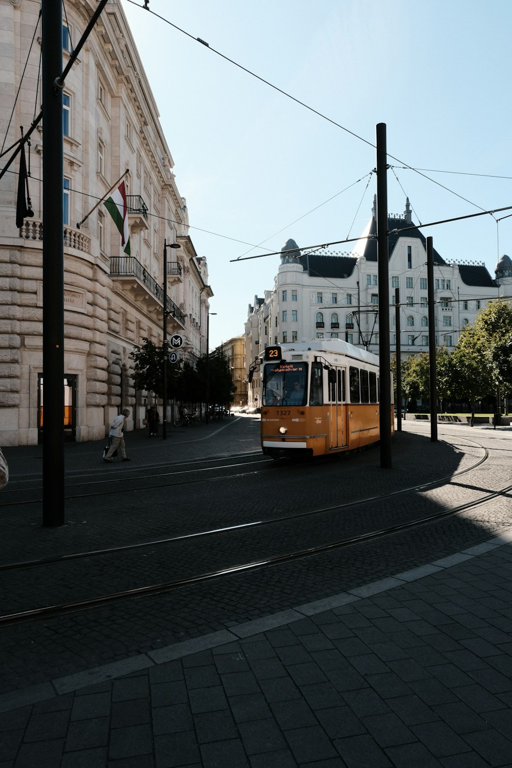 a yellow and white bus driving down a street next to tall buildings