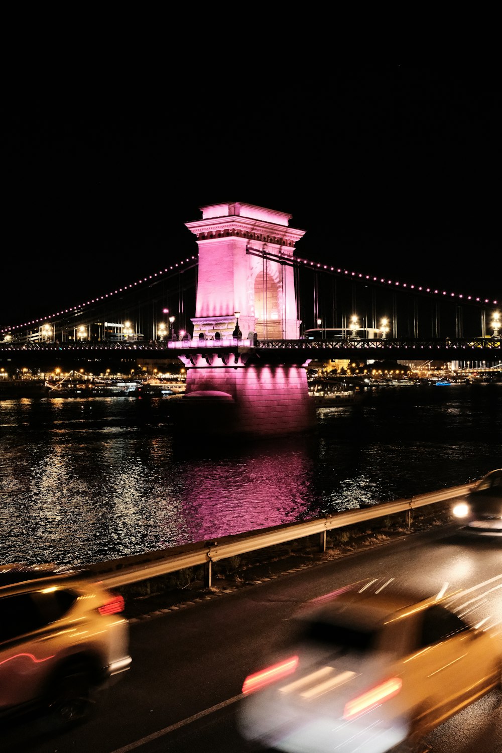 cars driving on a road near a bridge at night