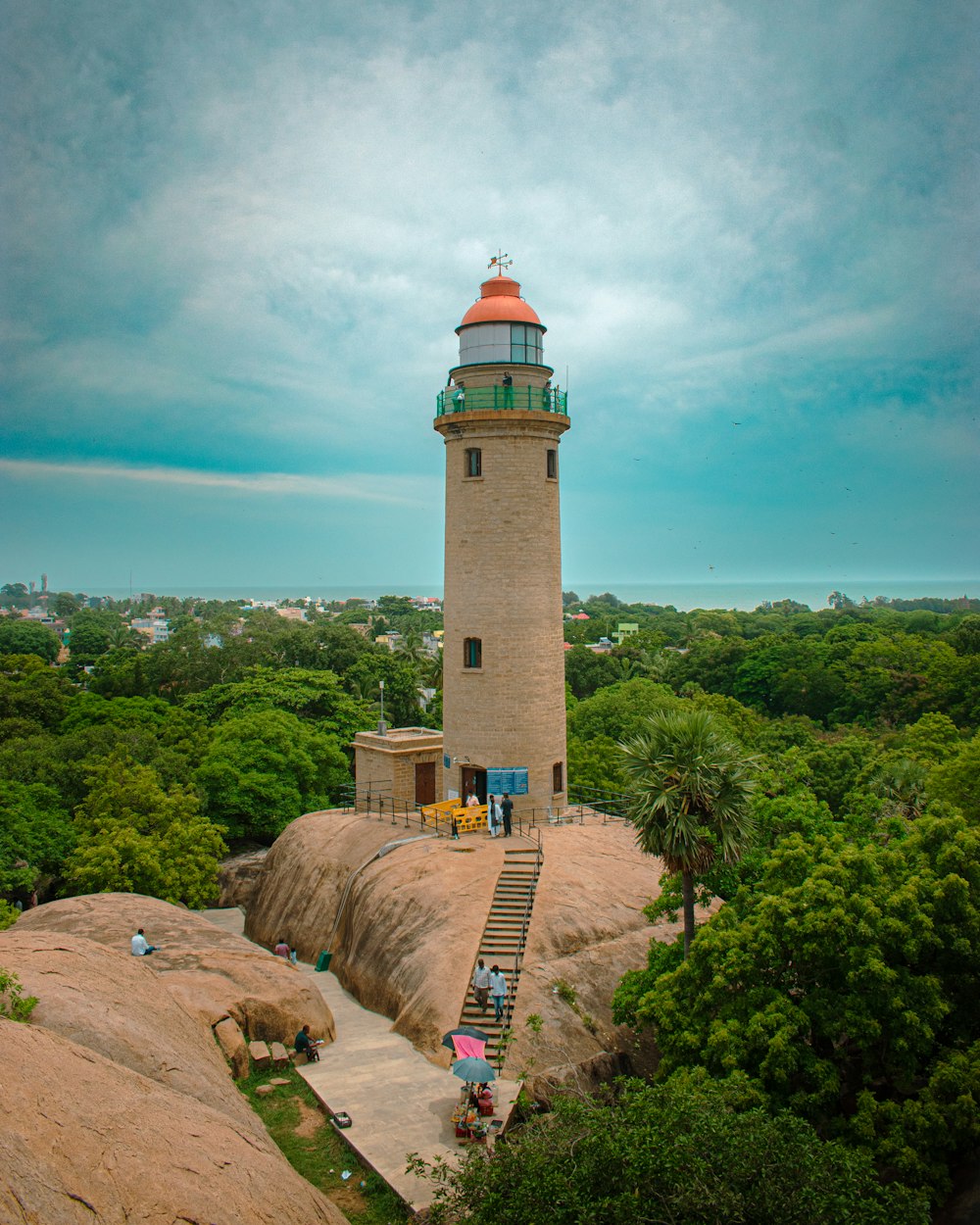 a lighthouse on top of a large rock surrounded by trees