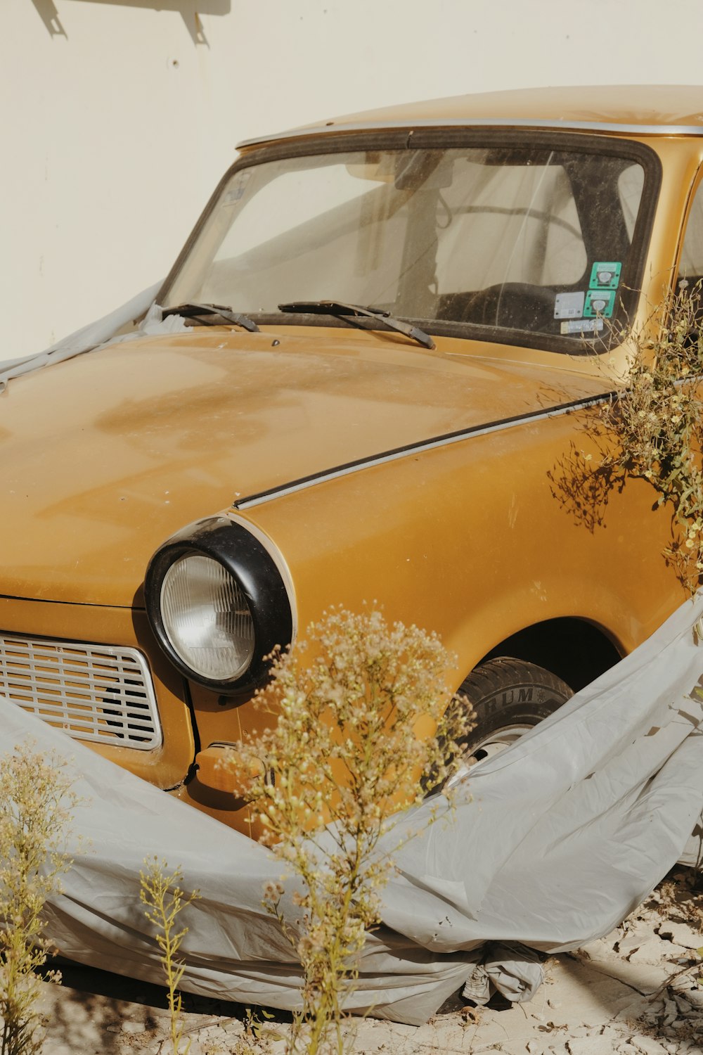 an old yellow car with a tarp covering it