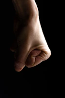 A close-up shot of a determined man’s clenched fist against a dark, textured background.