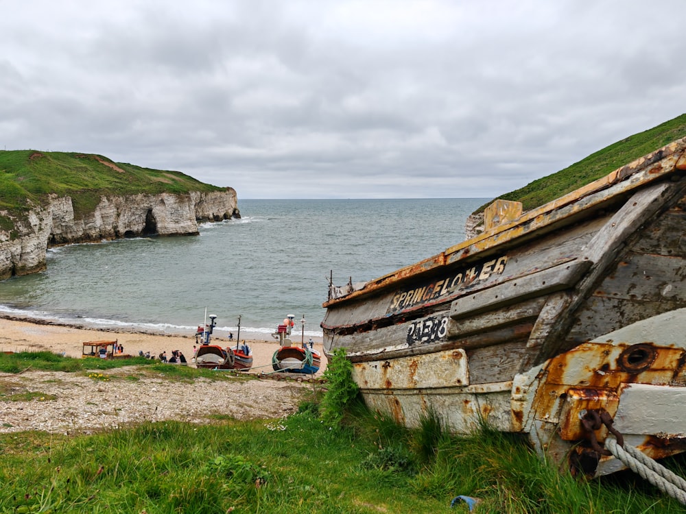 a boat sitting on top of a beach next to the ocean