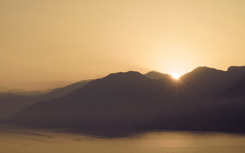 the sun is setting over a mountain range