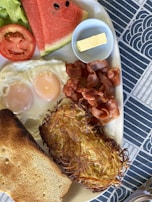 A colorful plate of classic American breakfast with eggs, crispy bacon, and toast.