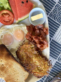 A sizzling skillet filled with crispy bacon, eggs sunny side up, and golden hash browns.