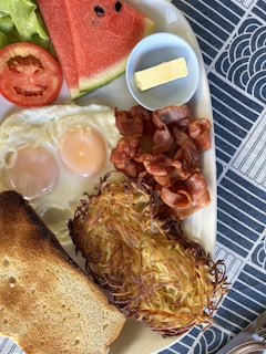 A colorful plate of classic American breakfast with eggs, crispy bacon, and toast.
