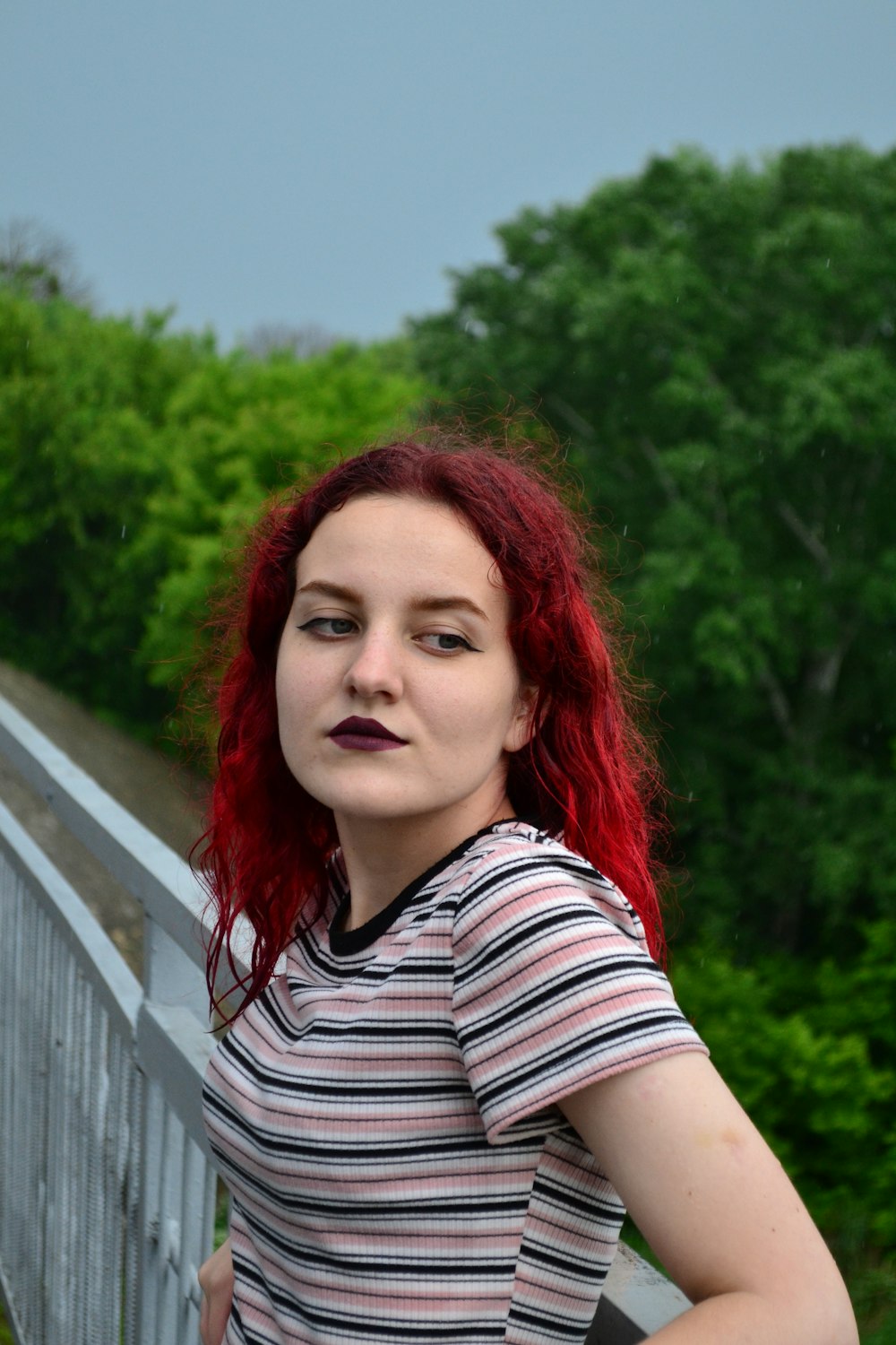a woman with red hair standing on a bridge