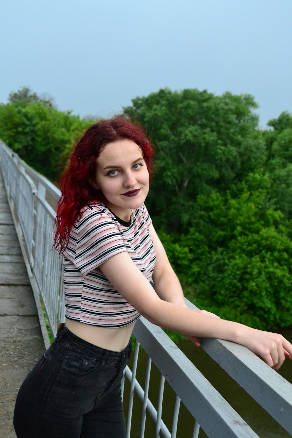 a woman with red hair standing on a bridge