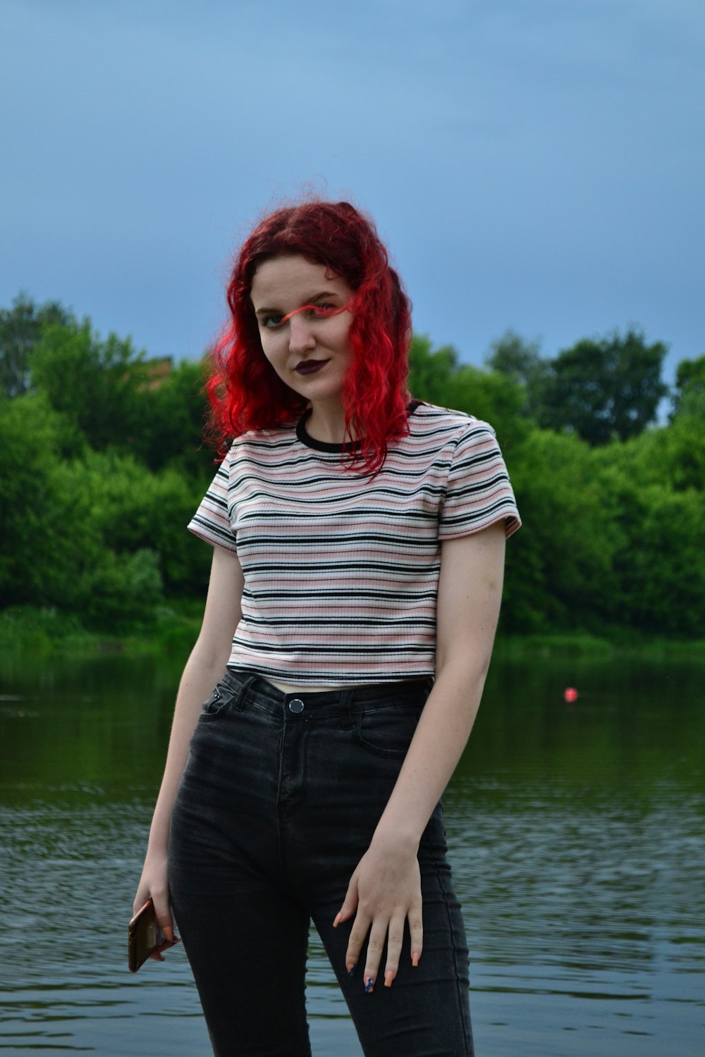 水域の前に立つ赤い髪の女性