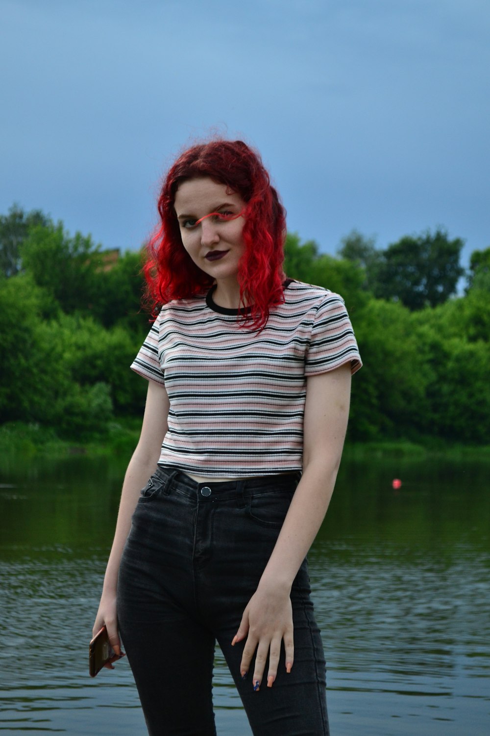 a woman with red hair standing in front of a body of water