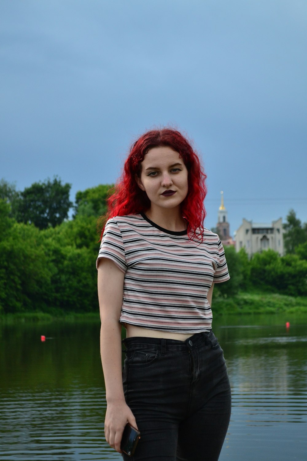 a woman with red hair standing in front of a body of water