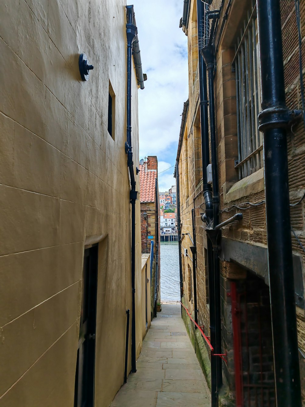 a narrow alley between two buildings next to a body of water