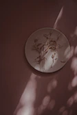 Sunlight casting warm shadows on a hand-painted clay plate with floral patterns.