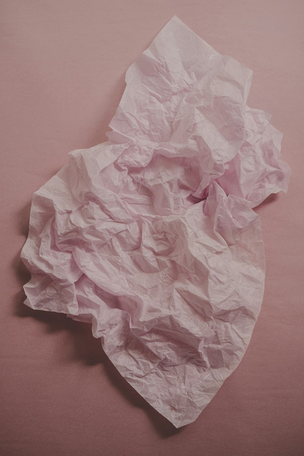 um pedaço de papel amassado em uma superfície rosa