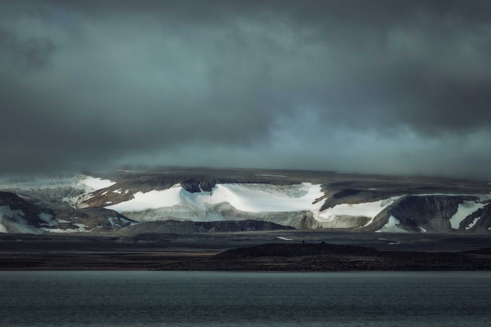 a large mountain covered in snow under a cloudy sky