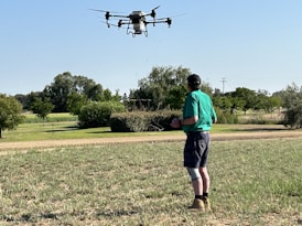 A student pilot receiving hands-on training with an agricultural drone in a field.