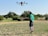 A satisfied farmer standing in a field with a drone.