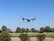 Close-up of a drone flying over a vibrant agricultural field under a clear blue sky.