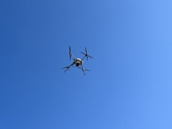 A prototype unmanned drone being tested outdoors against a clear blue sky.