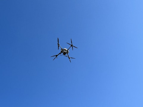 A student expertly piloting a drone outdoors against a clear blue sky.