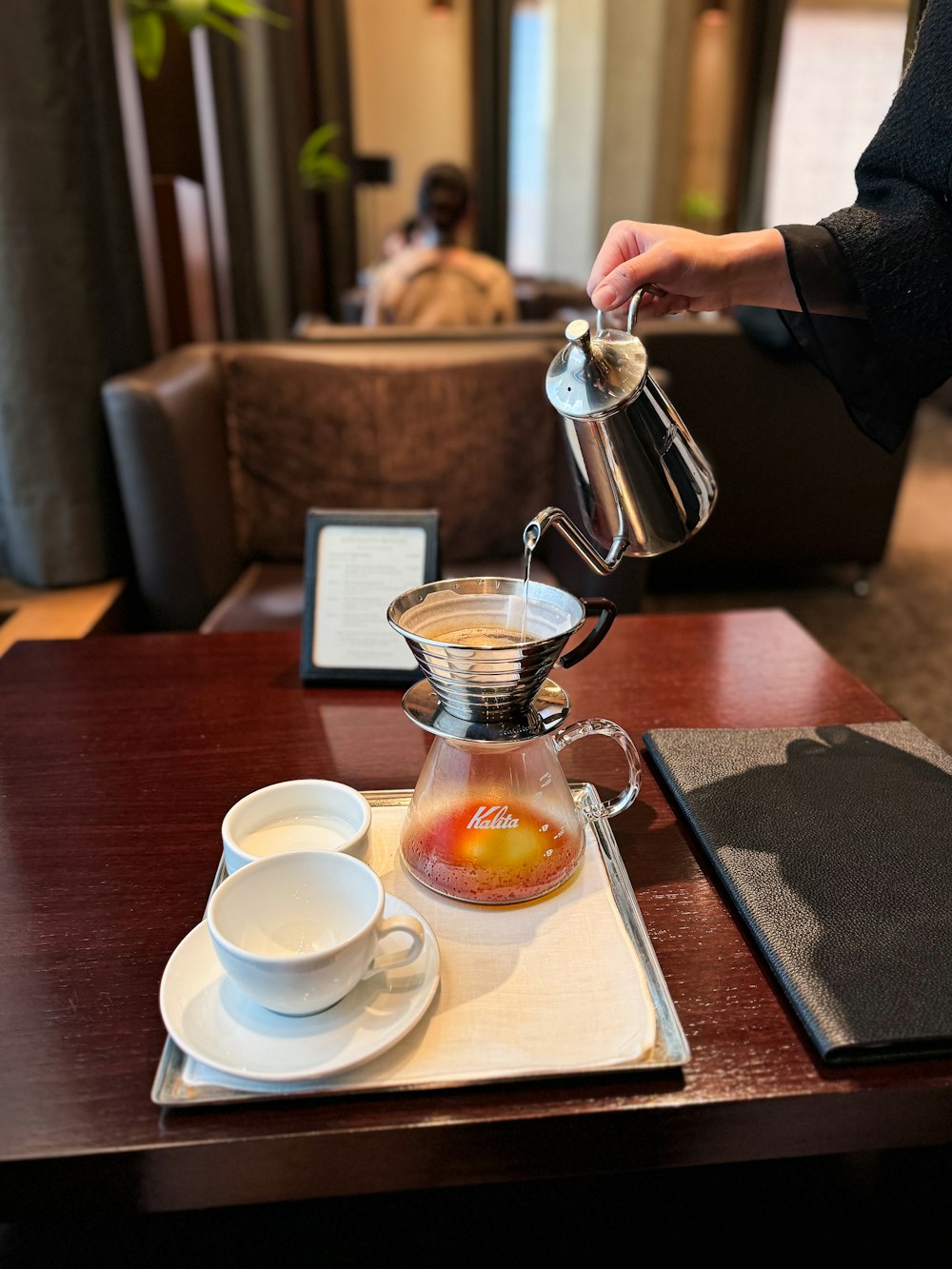 a person pours a cup of coffee on a table