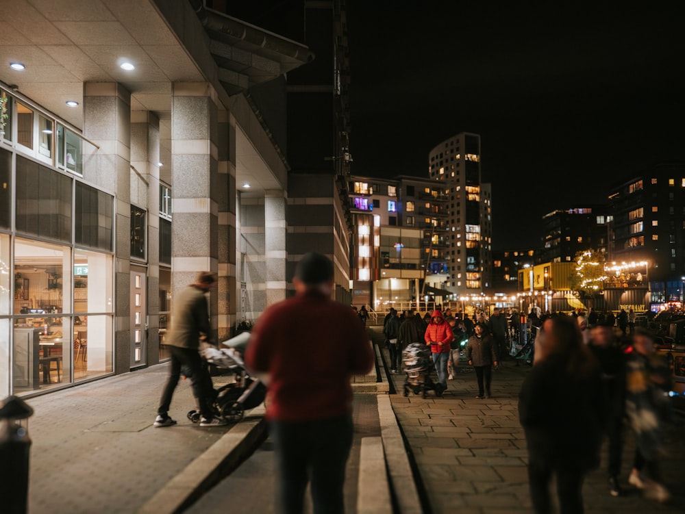 a group of people walking down a sidewalk next to tall buildings