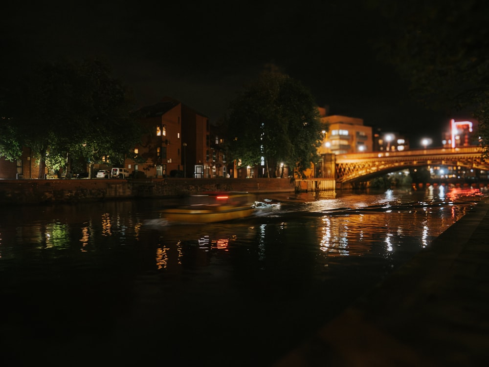 um rio à noite com uma ponte e edifícios ao fundo