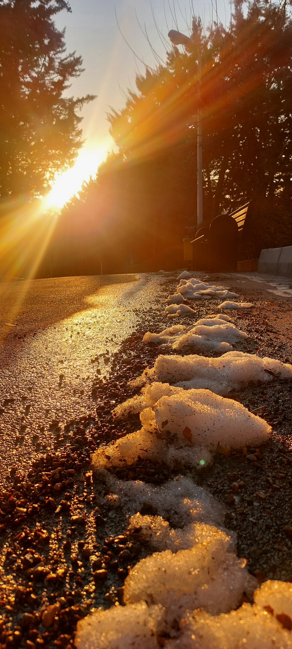 the sun is setting over a road with snow on it