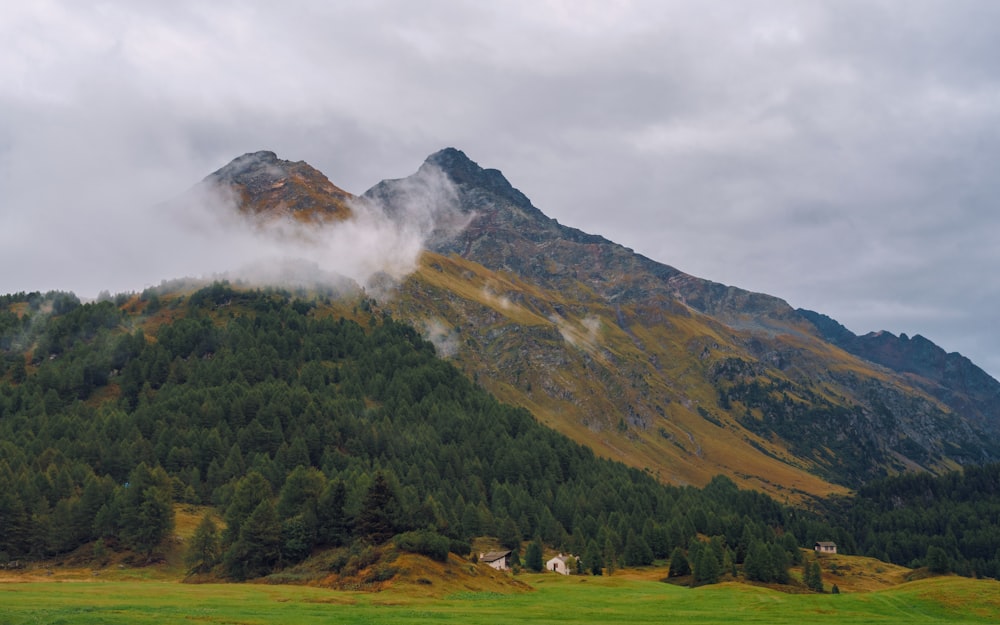 Ein Berg, der an einem bewölkten Tag mit Wolken und Bäumen bedeckt ist