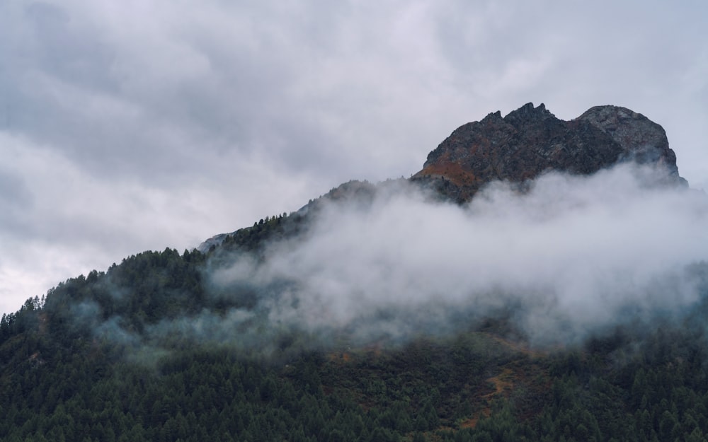 a mountain covered in fog and clouds on a cloudy day