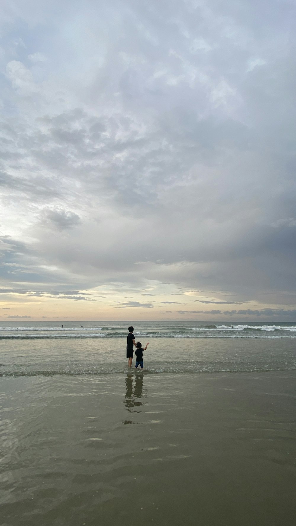 a couple of people standing on top of a sandy beach