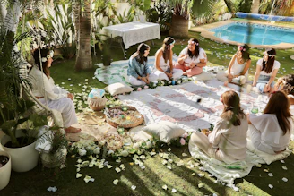 a group of women sitting on top of a lush green field