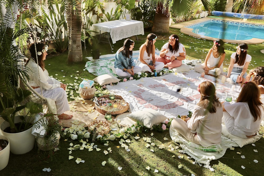 a group of women sitting on top of a lush green field