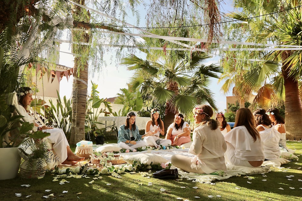 a group of women sitting on top of a lush green field