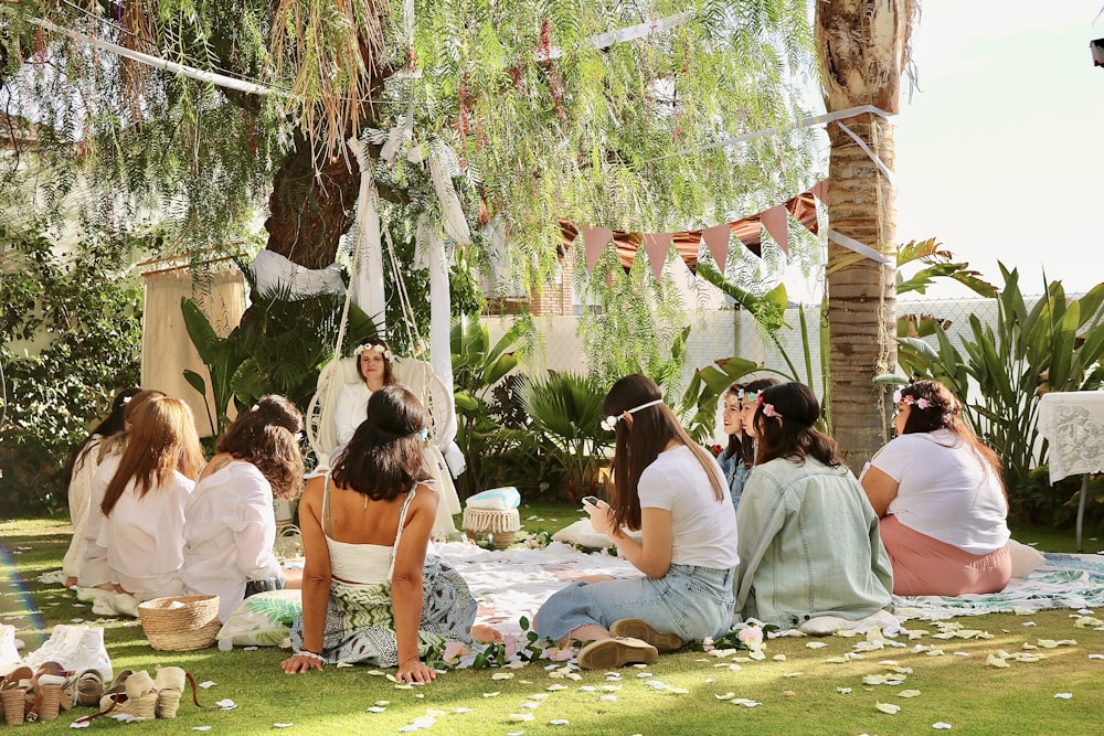 a group of women sitting on top of a lush green field