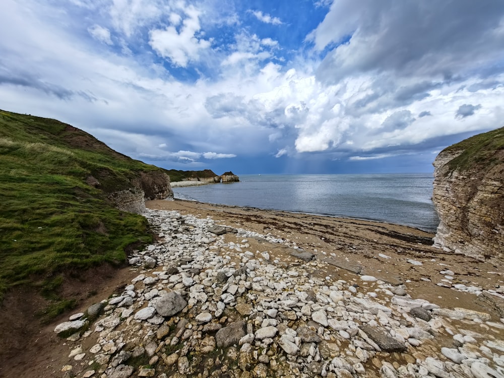 a rocky beach next to the ocean under a cloudy sky