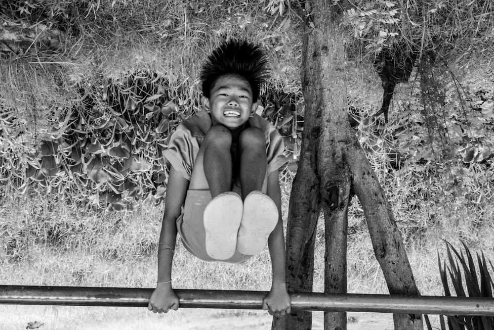 a young boy hanging upside down on a fence