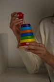 A close-up of hands assembling a language development toy with soft blue accents.