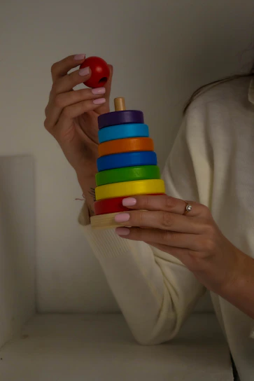 Close-up of a child's hands assembling a wooden stacking toy with bright colors.